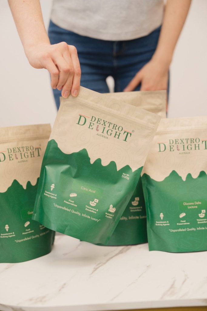 Top-down view of Dextro Delight Australia bags on a marble table with a hand picking up one bag