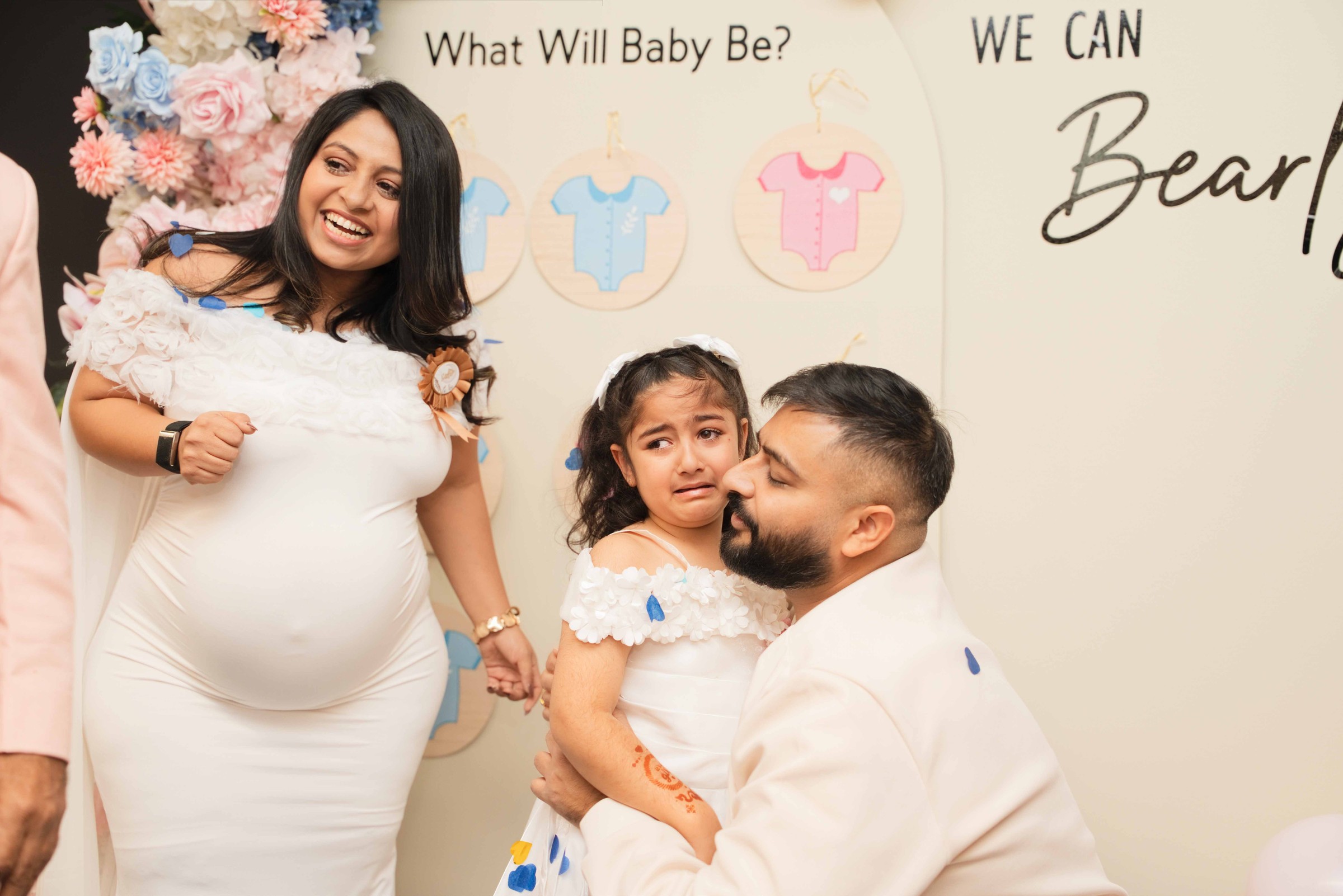 Tarak, Honey and a young girl posing in front of the gender reveal backdrop