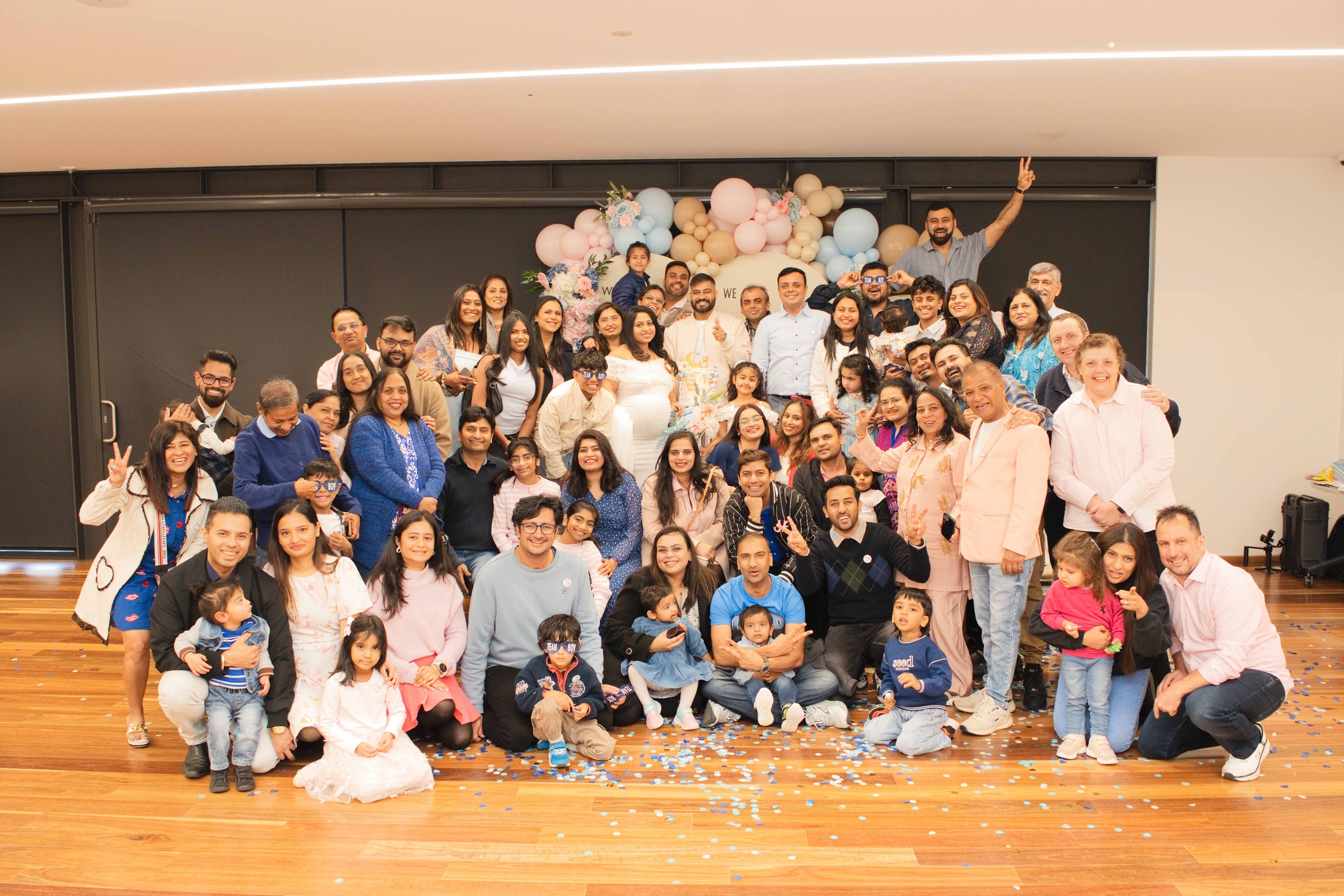 Family and friends cheering with confetti scattered across the floor after the reveal