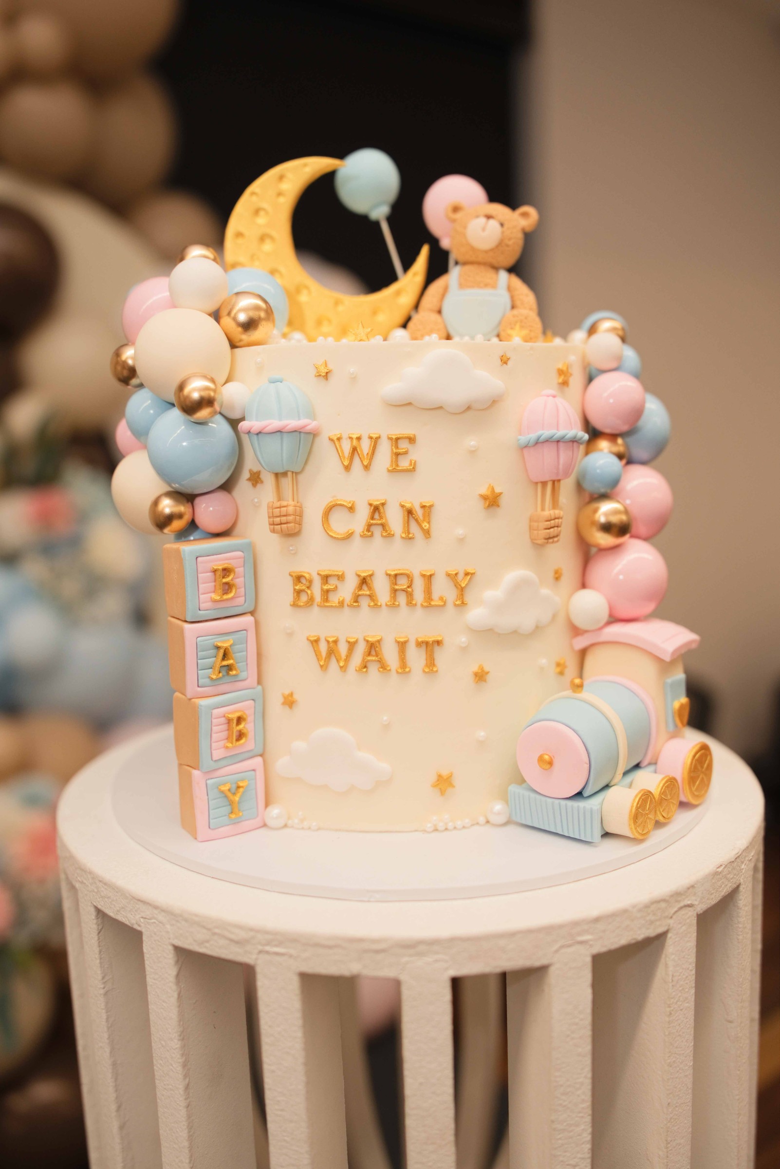 Three-tier blue and cream gender reveal cake decorated with teddy bears, a moon and stars