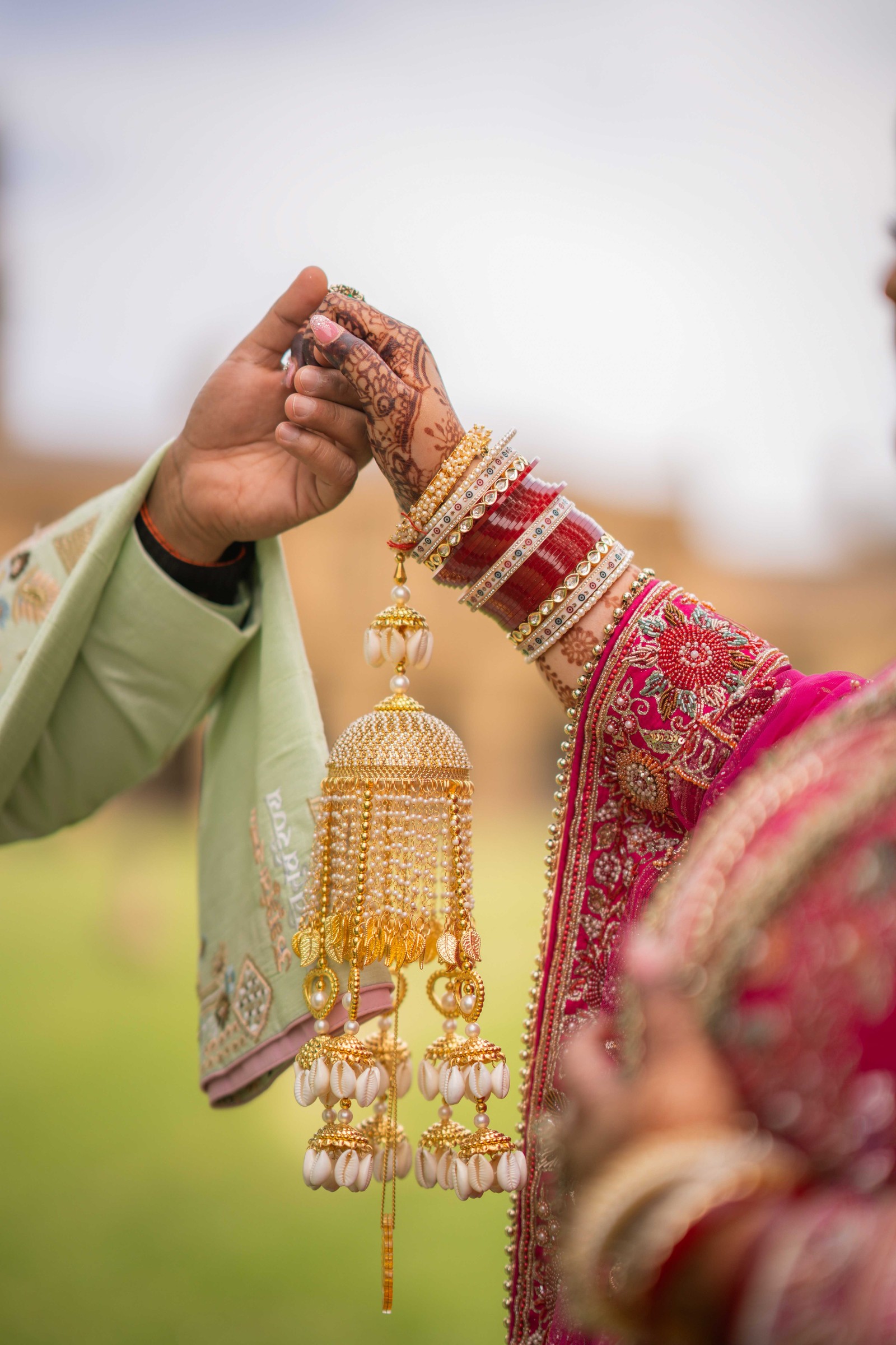 Close-up of the couple's joined hands showing intricate bridal henna and ornate gold wrist jewellery