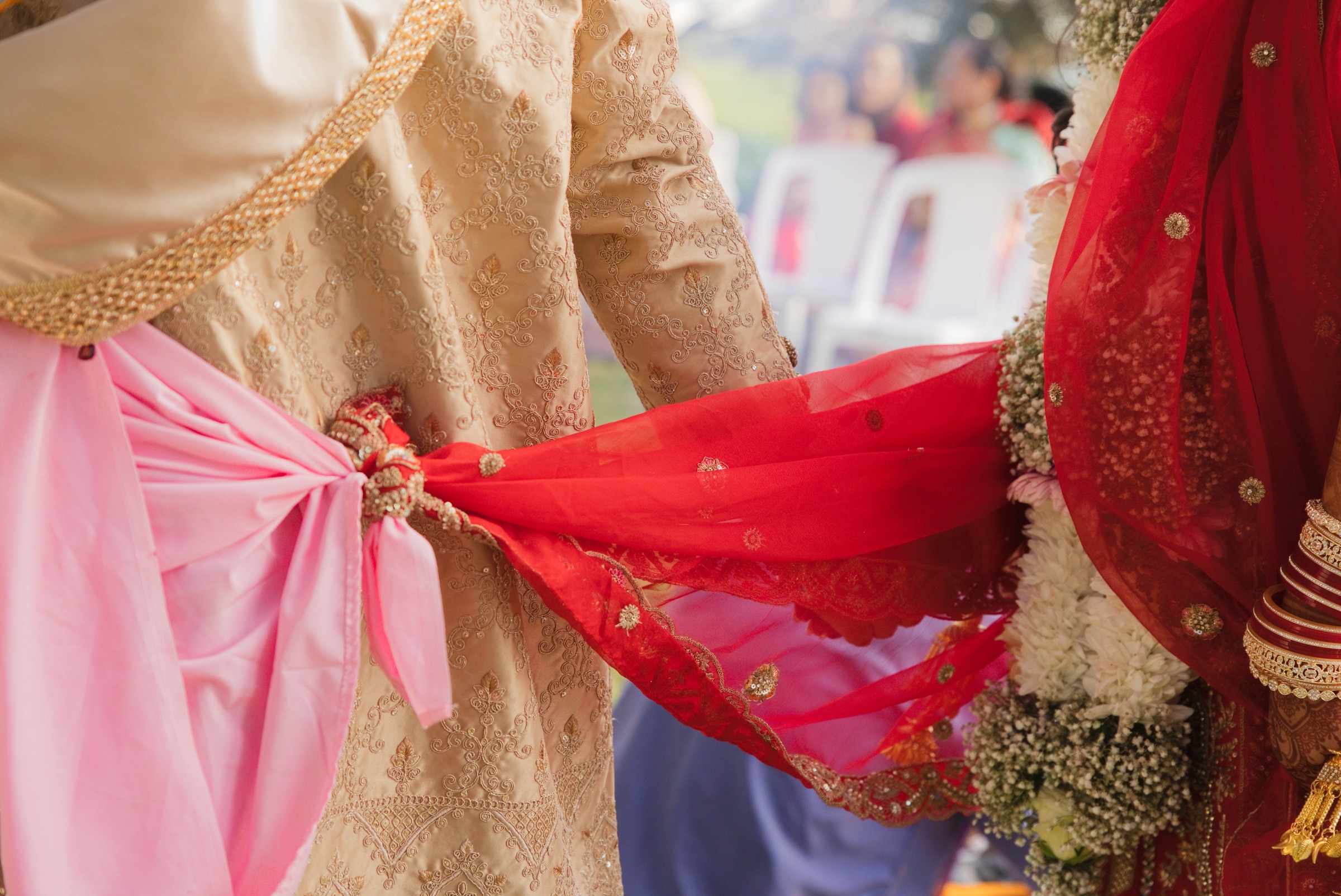 Close-up of the couple's sash and dupatta tied together during a wedding ritual